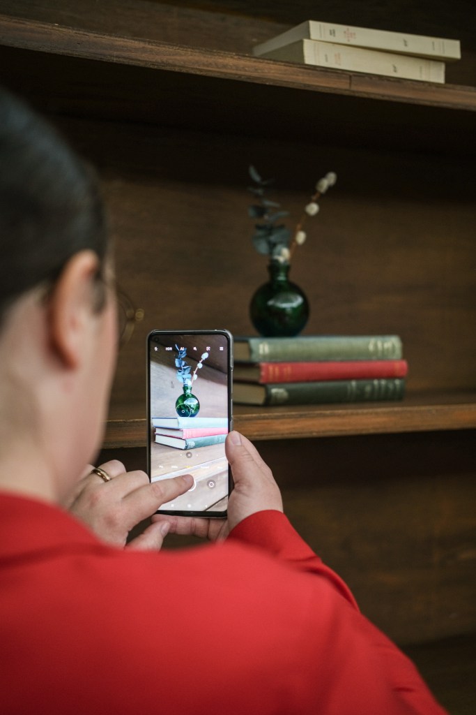 Photo de Julia Portzenem, rédactrice en chef des chroniques d'une nantaise, en train de prendre en photo une pile de livres pour en faire un post sur les réseaux sociaux avec son téléphone. 
